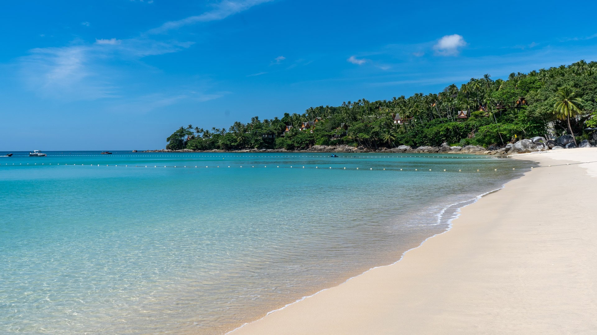 Shallow turquoise swimming area along calm waterline.