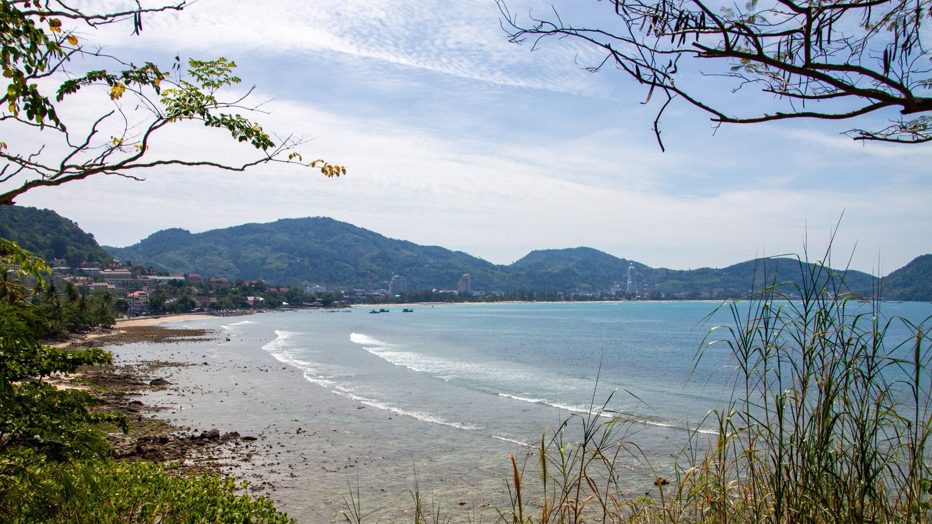 Kalim Beach Phuket roadside view with rocks, trees, and beach below