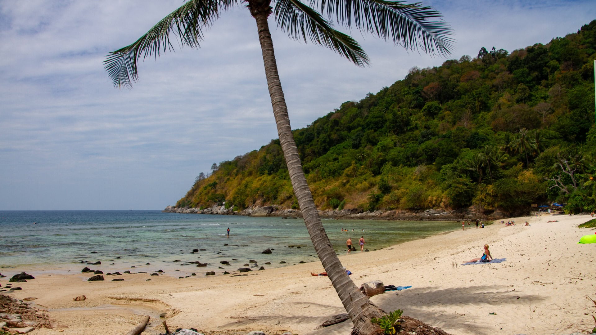 Merlin Beach Phuket with leaning palm tree, white sand, and shallow rocky shoreline